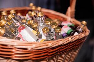 sortiert Miniatur Flaschen von Alkohol im ein gewebte Korb beim ein Bar foto