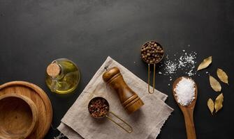 Salz, Piment, Pfefferkörner und Olive Öl im ein Flasche auf ein schwarz Tabelle foto