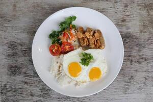 Knoblauch Pfeffer longaniza mit sonnig Ei und Reis mit Tomate mit Salat serviert im Gericht isoliert auf hölzern Hintergrund oben Aussicht von Frühstück foto