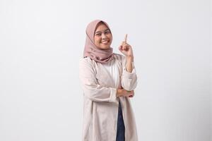 Porträt von aufgeregt asiatisch Hijab Frau im beiläufig passen zeigen oben ihr Zeigefinger und erinnern etwas zu Tun. Geschäftsfrau Konzept. isoliert Bild auf Weiß Hintergrund foto