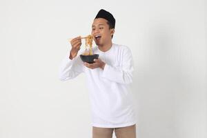 Porträt von aufgeregt asiatisch Muslim Mann Essen köstlich sofortig Nudeln mit Essstäbchen serviert auf Platte. Vor Dämmerung Mahlzeit und brechen Fasten Konzept. isoliert Bild auf Weiß Hintergrund foto