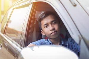 Porträt von nachdenklich jung asiatisch Teenager Fahren seine Auto und suchen beim Kamera foto