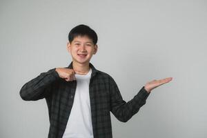 Teen Mann Junge mit Hosenträger präsentieren mit Hand Geste. asiatisch Teen Junge mit Dental Hosenträger Herstellung ein präsentieren Geste auf ein einfach Hintergrund. Porträt gut aussehend Mann im Studio Konzept. foto