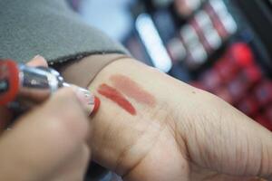 ein Geste von bewirbt sich karminrot Lippenstift zu das Fleisch von Ein weiterer Personen Hand foto