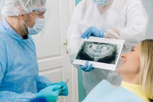 das Zahnarzt zeigt an das Einzelheiten von das Röntgen zu seine geduldig im das Arzt Büro foto
