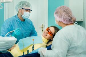 das geduldig lächelt im das Zahnarzt Stuhl im ein schützend Maske und Instrument Vor Behandlung im das Dental Büro foto