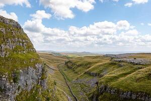 szenisch Aussicht von ein üppig Grün Senke mit felsig Klippen unter ein wolkig Himmel beim Malham Bucht, Yorkshire, Vereinigtes Königreich. foto