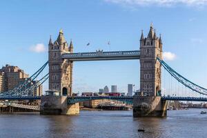 Londons ikonisch Turm Brücke gegen ein klar Blau Himmel, mit Stadt Gebäude im das Hintergrund. foto
