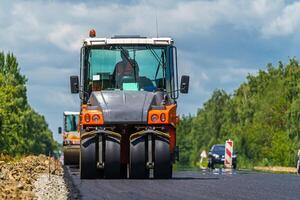 Straße Walze Abflachung Neu Asphalt. schwer Vibration Walze beim Arbeit Pflasterung Asphalt, Straße reparieren. selektiv Fokus. foto