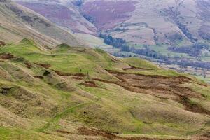 rollen Grün Hügel mit texturiert Landschaft und ein Schlucht, unter ein wolkig Himmel im Gipfel Bezirk, England. foto