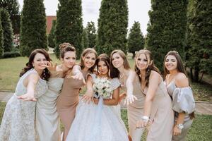 Hochzeit Fotografie. ein Brünette Braut im ein Weiß Kleid mit ein Strauß und ihr Brünette Freundinnen foto