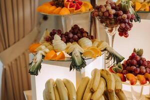 ein Bankett Tabelle voll von Früchte und Beeren, ein Sortiment von Süßigkeiten. Bananen, Trauben, Ananas. Obst Kompositionen zum das Urlaub. foto