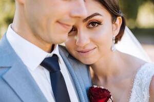 Porträt von ein lächelnd Braut mit ein Strauß von Blumen umarmen ihr Mann während suchen beim das Kamera. schön Hochzeit Feier. Hochzeit Frisur mit ein Schleier. Paar im Liebe. foto
