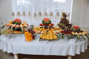 ein Bankett Tabelle voll von Früchte und Beeren, ein Sortiment von Süßigkeiten. Bananen, Trauben, Ananas. Obst Kompositionen zum das Urlaub. foto