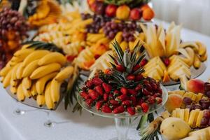 ein Bankett Tabelle voll von Früchte und Beeren, ein Sortiment von Süßigkeiten. Bananen, Trauben, Ananas. Obst Kompositionen zum das Urlaub. foto