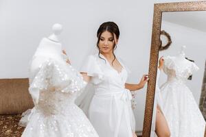 im das Morgen, ein unglaublich schön und luxuriös Braut, gekleidet im ein Weiß Kleid, posiert durch das Spiegel im ihr Schlafzimmer. Morgen von das Braut mit ein luxuriös Frisur und natürlich bilden. foto