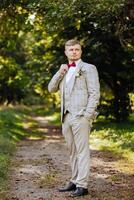 Porträt von ein gut aussehend jung Bräutigam auf ein Herbst Tag draußen im ein elegant Anzug. draussen Foto. gut aussehend Mann im ein Geschäft Anzug. foto