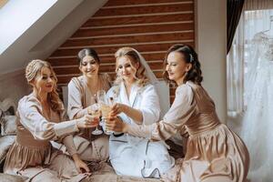 Foto mit Brautjungfern Trinken Champagner von Brille im das Morgen im ein schön Hotel. Foto von ein schön jung Braut und ihr freunde im passend Kleider Trinken Champagner Vor das Hochzeit.