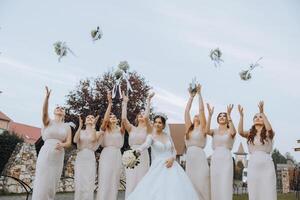 Hochzeit Fotografie. ein Brünette Braut im ein Weiß Kleid mit ein Strauß und ihr Brünette Freundinnen foto