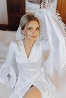 Nahansicht blond Braut mit Mode Hochzeit Frisur und bilden. ein jugendlich Braut mit ein anspruchsvoll Braut- Frisur drinnen durch ein Fenster foto