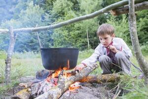 slawisch Kind im National Kleider in der Nähe von das Feuer. ukrainisch Junge im Natur. weißrussisch foto