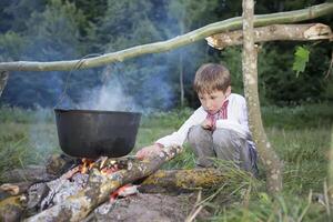 slawisch Kind im National Kleider in der Nähe von das Feuer. ukrainisch Junge im Natur. weißrussisch foto