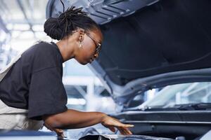 bipoc Frau im Auto Bedienung mit Fachmann mechanisch Werkzeug zu Reparatur gebrochen Zündung System. erfahren Spezialist im Garage Festsetzung Klient Automobil, gewährleisten optimal Automobil Performance foto