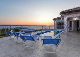 Terrasse mit Pool und Liegestühlen bei Sonnenuntergang foto