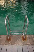 ein rostfrei Stahl Schwimmen Leiter im ein Schwimmen Schwimmbad mit Türkis Wasser foto
