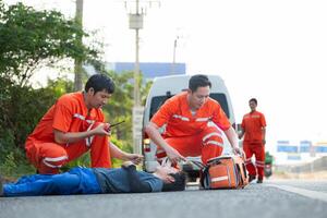 das Sanitäter ist assistieren ein verletzt Mann im ein Notfall Situation auf das Straße. foto