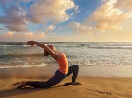 sportlich passen Frau Praktiken Methoden Ausübungen Yoga anjaneyasana beim Strand auf Sonnenuntergang foto