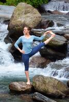 Frau tun Ashtanga Vinyasa Yoga Asana draußen beim Wasserfall foto