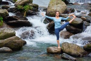 Frau tun Ashtanga Vinyasa Yoga Asana draußen beim Wasserfall foto