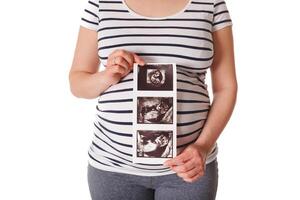 schwanger Frau Stehen und halten ihr Ultraschall Baby Scan foto