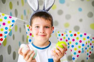 süß Junge mit Hase Ohren halten Ostern Eier. foto