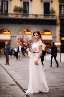 das Mädchen-Braut ist mit schön Blume Muster wie ein Maske im Florenz, stilvoll Braut im ein Hochzeit Kleid Stehen mit ein Maske im das alt Stadt, Dorf von Florenz. Modell- Mädchen im Florenz foto