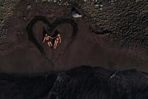 ein Paar im Liebe Lügen auf ein Strand von schwarz vulkanisch Sand im ein gemalt Herz, Teneriffa, Kanarienvogel Inseln, Spanien foto