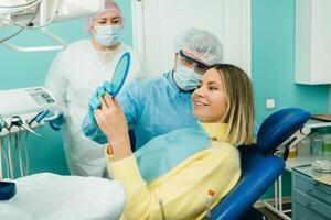 das Zahnarzt zeigt an das Klient das Ergebnisse von seine Arbeit im das Spiegel foto