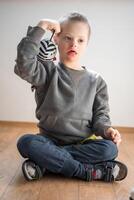 Porträt von klein Junge mit Nieder Syndrom spielen mit Spielzeug im Zuhause Schlafzimmer. hoch Qualität Foto