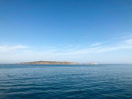 Insel im ein Ruhe Meer. Aussicht von das Schiff. Ruhe Wasser, Insel und klar sonnig Tag foto