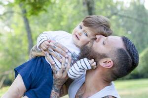 tätowiert Vater haben Spaß mit seine Sohn im das Park foto