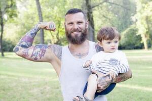 tätowiert Vater haben Spaß mit seine Sohn im das Park foto