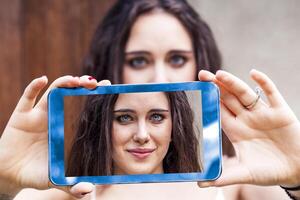 jung tausendjährig Frau nehmen ein Selfie mit Clever Telefon draußen foto