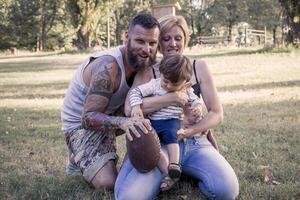 jung Paar mit Kind haben Spaß beim das Park mit Rugby Ball foto