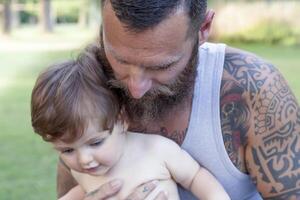 tätowiert Vater haben Spaß mit seine Sohn im das Park foto