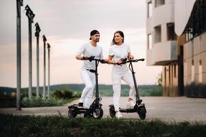 ein Mädchen und ein Kerl sind Gehen auf elektrisch Roller um das Stadt, ein Paar im Liebe auf Roller. foto