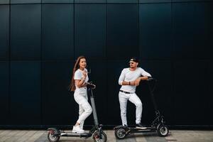 ein Mädchen und ein Kerl sind Gehen auf elektrisch Roller um das Stadt, ein Paar im Liebe auf Roller. foto