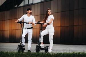 ein Mädchen und ein Kerl sind Gehen auf elektrisch Roller um das Stadt, ein Paar im Liebe auf Roller. foto