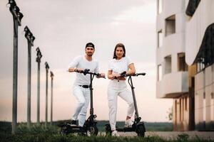 ein Mädchen und ein Kerl sind Gehen auf elektrisch Roller um das Stadt, ein Paar im Liebe auf Roller. foto