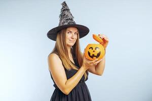 glücklich jung Frau im Halloween Hexe Kostüm mit Kürbis Korb Kürbislaterne foto